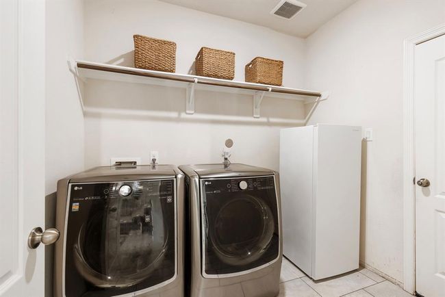This generously sized laundry room includes shelving, as well as a space for an extra refrigerator or deep freezer. | Image 28