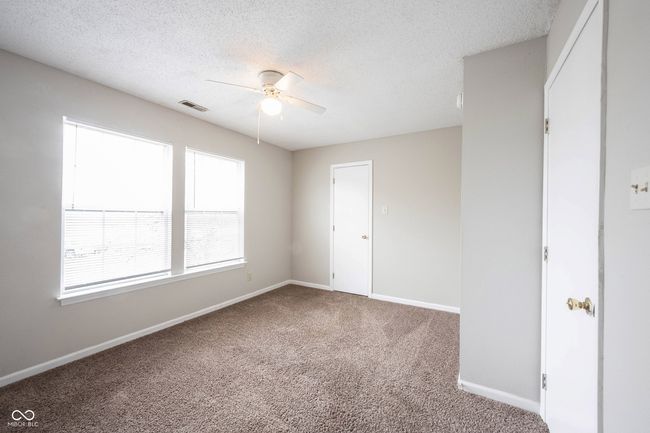 carpeted empty room with a textured ceiling, visible vents, baseboards, and ceiling fan | Image 22