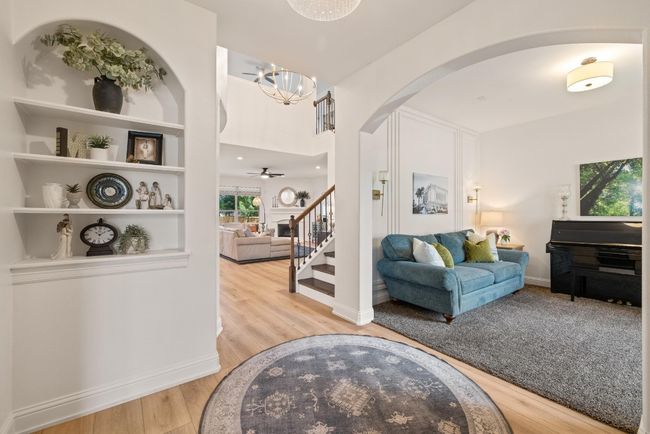 Living area with stairs, wood finished floors, baseboards, a chandelier, and arched walkways | Image 17