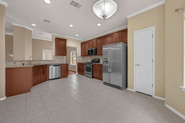 . The open-concept kitchen is a chef’s dream, offering granite countertops, stainless steel appliances, recessed lighting, cherry cabinetry with pull-out shelves, and a convenient breakfast bar overlooking the living room. | Image 12