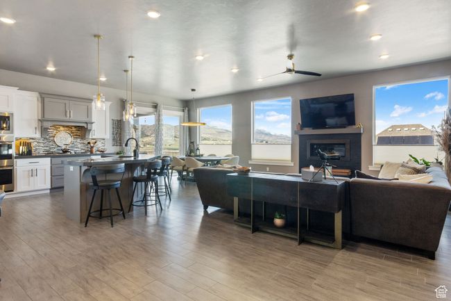 Living area with a ceiling fan, a glass covered fireplace, wood finished floors, and recessed lighting | Image 10