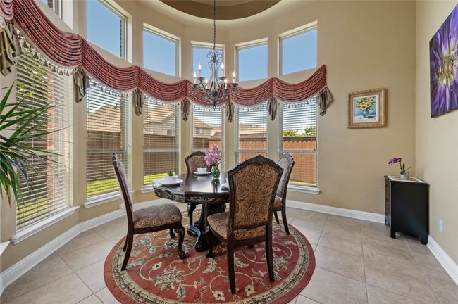 Dining area featuring healthy amount of natural light, a chandelier, light tile patterned floors, and a towering ceiling | Image 13