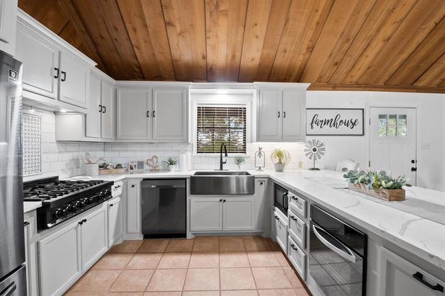 This renovated kitchen offers quartz counters that complement the cabinets and subway tile backsplash. Under-cabinet lighting and 6 burner gas stove are a few of the highlights. | Image 6