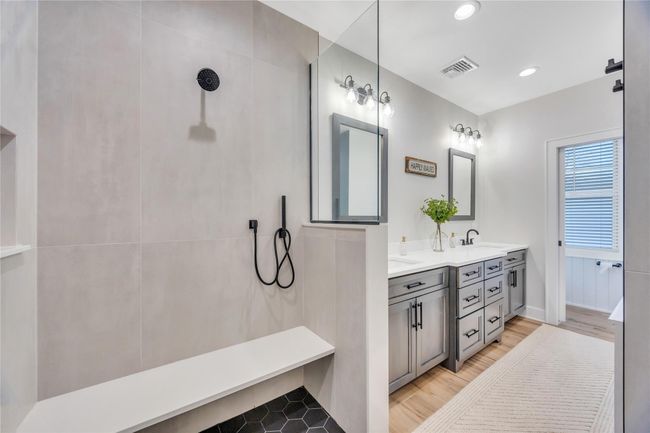 Bathroom featuring tiled shower, a sink, wood finished floors, visible vents, and double vanity | Image 25