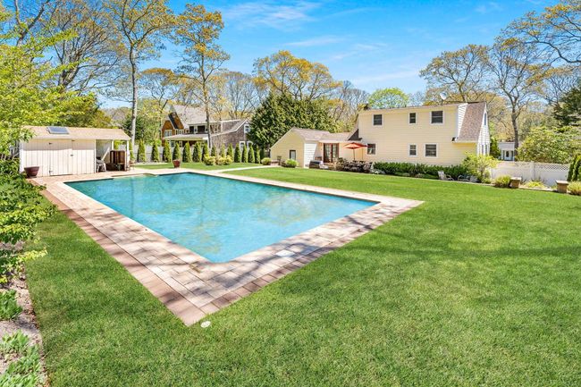 View of swimming pool featuring a storage shed and a lawn | Image 4