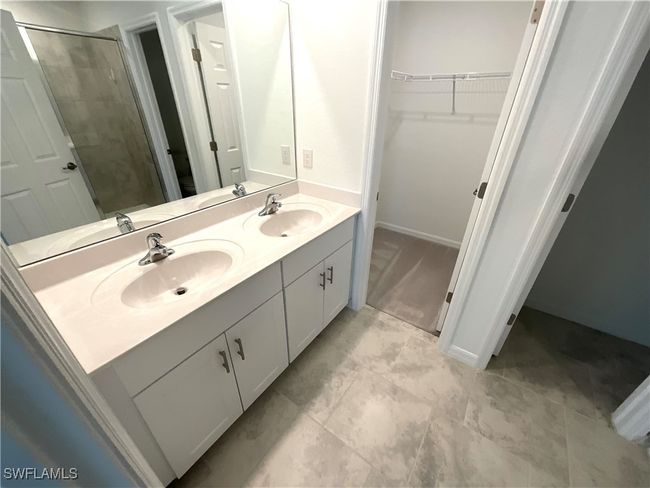 Bathroom featuring a walk in closet, a stall shower, and double vanity | Image 11