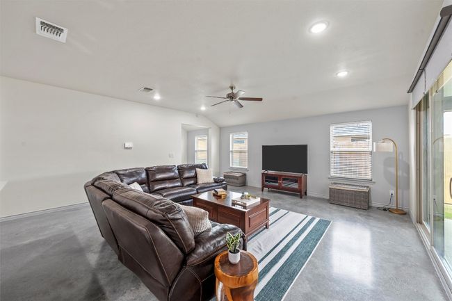 Living area featuring visible vents, finished concrete floors, ceiling fan, and a healthy amount of sunlight | Image 5