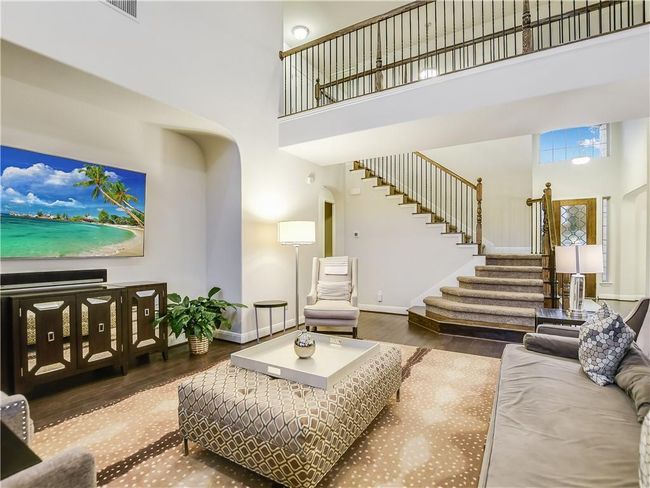 Living area featuring arched walkways, a high ceiling, wood finished floors, and stairs | Image 8