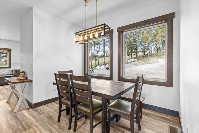 Dining area with a notable chandelier, visible vents, wood finished floors, and baseboards | Image 11
