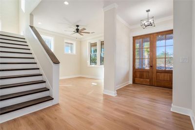 Entrance foyer featuring ceiling fan with notable chandelier, light hardwood / wood-style floors, crown molding, and french doors | Image 3