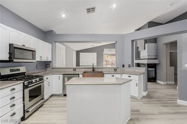 Kitchen, appliances with stainless steel finishes, copper sink, a center island, light wood-type flooring. | Image 11