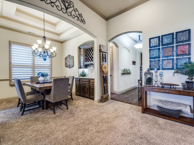 Dining space featuring arched walkways, light colored carpet, a chandelier, ornamental molding, and baseboards | Image 6