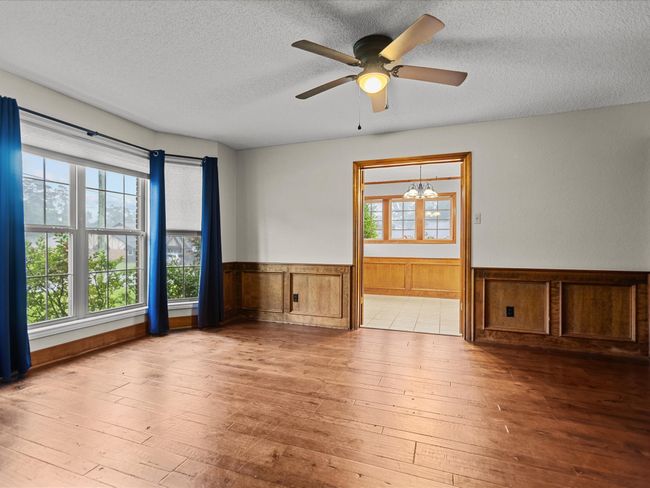 Unfurnished room featuring hardwood / wood-style flooring, wainscoting, a textured ceiling, a ceiling fan, and wooden walls | Image 12