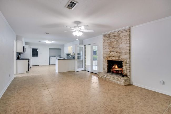Family room with easy care tile flooring features a wood burning fireplace. | Image 18