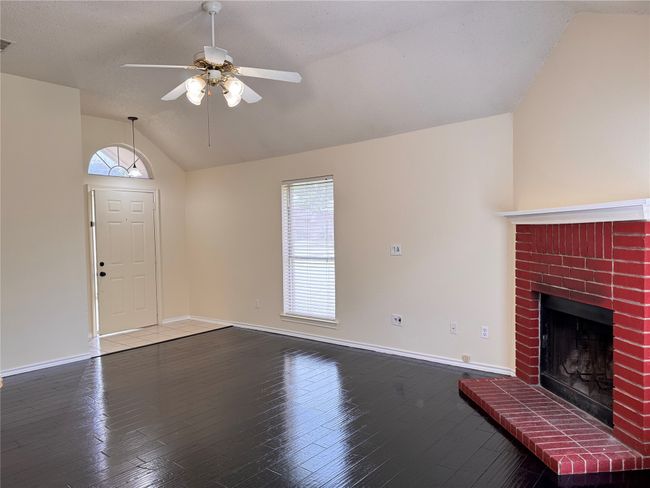 Unfurnished living room featuring lofted ceiling, ceiling fan, baseboards, hardwood / wood-style floors, and a fireplace | Image 5