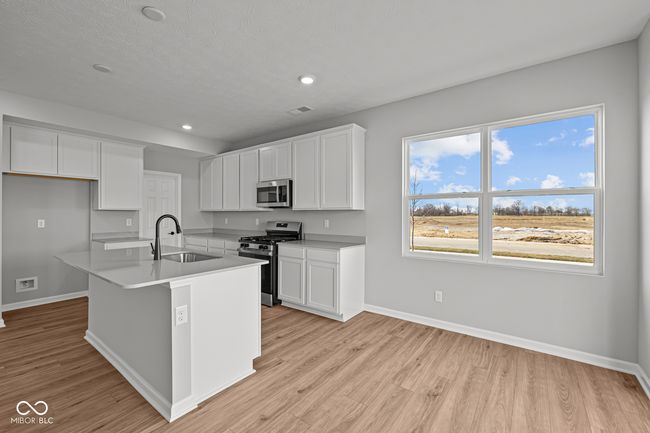kitchen featuring light wood-type flooring, baseboards, a sink, white cabinets, and appliances with stainless steel finishes | Image 6
