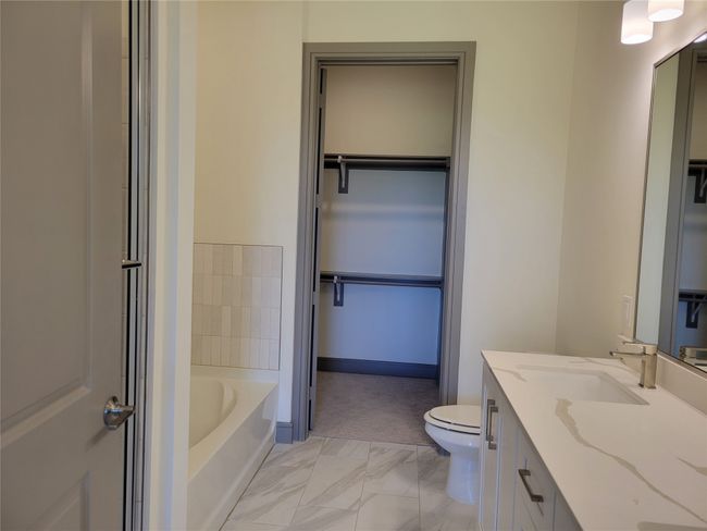 Full bathroom with a spacious closet, toilet, a tub, and vanity | Image 11