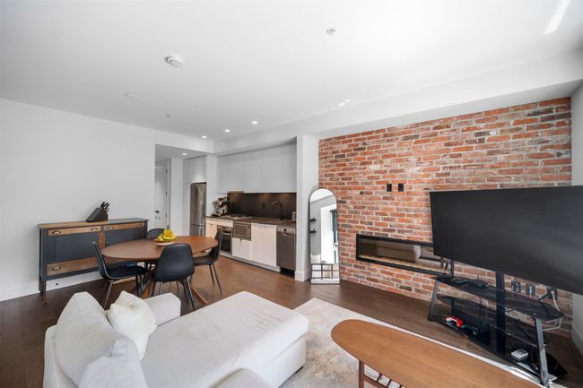 Living area featuring brick wall, wood finished floors, recessed lighting, a glass covered fireplace, and arched walkways | Image 8