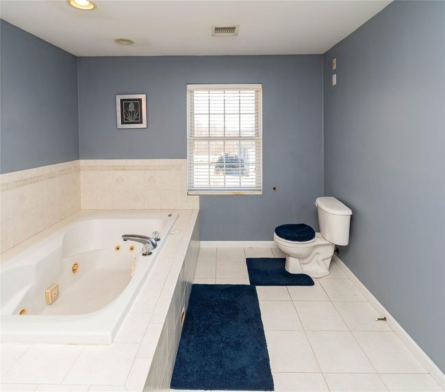Full bathroom with tile patterned flooring, visible vents, baseboards, toilet, and a tub with jets | Image 30