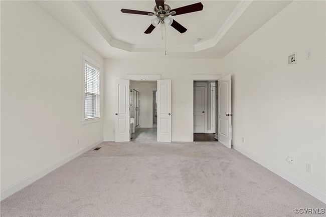Unfurnished bedroom with a raised ceiling, carpet flooring, crown molding, and ceiling fan | Image 29