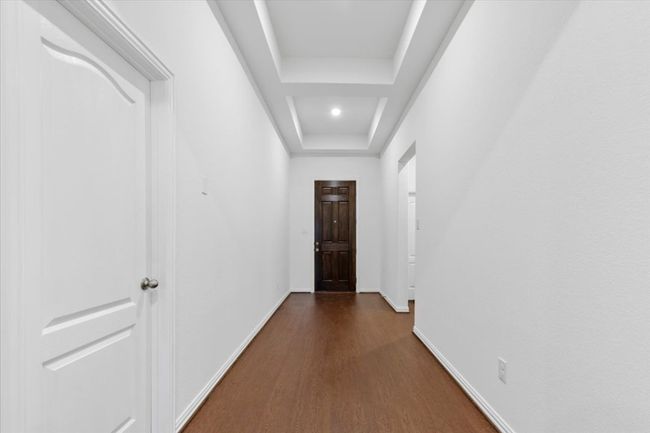 Corridor with baseboards, dark wood-style flooring, and a raised ceiling | Image 6