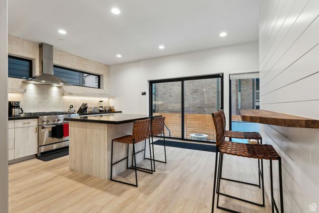Kitchen with ventilation hood, stainless steel stove, light hardwood / wood-style floors, and a center island | Image 7