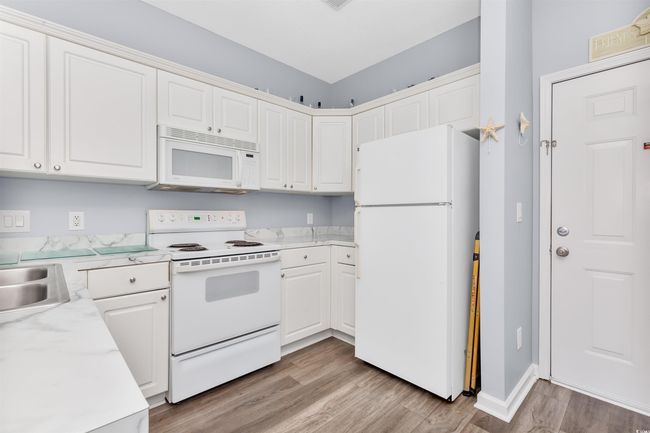Kitchen featuring white appliances, light wood-style floors, light countertops, and white cabinetry | Image 4
