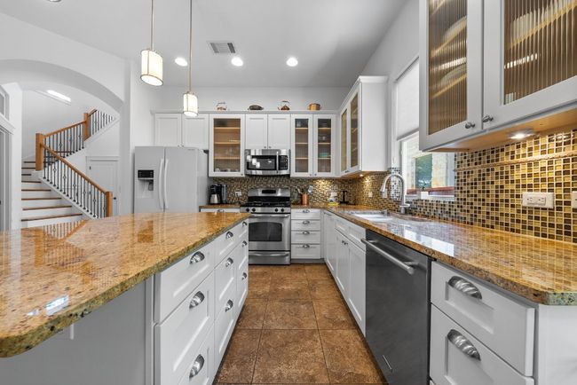 Kitchen featuring tasteful backsplash, visible vents, appliances with stainless steel finishes, a sink, and decorative light fixtures | Image 11