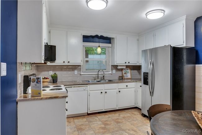 Updated kitchen with stainless steel fridge, dishwasher, decorative backsplash, and white cabinetry, eat-in kitchen with quartzite countertopos, custom built-in pantry & bar area, new lighting | Image 12