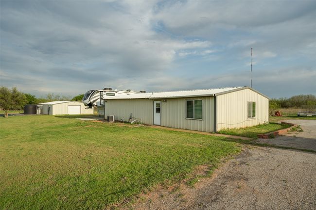 View of front of home with an outdoor structure, a front yard, central air condition unit, and metal roof | Image 39