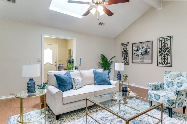 Living area with ceiling fan, wood finished floors, high vaulted ceiling, beam ceiling, and a skylight | Image 7
