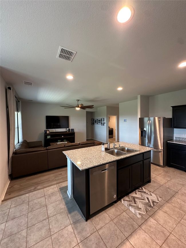 Kitchen featuring an island with sink, stainless steel appliances, visible vents, a sink, and ceiling fan | Image 19