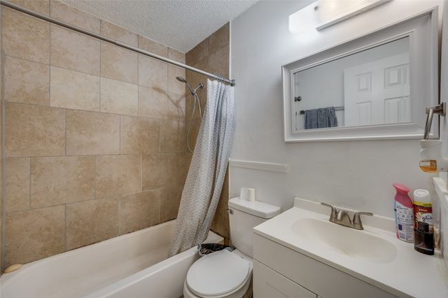 Unit B Full bathroom with toilet, vanity, shower / bath combination with curtain, and a textured ceiling | Image 25