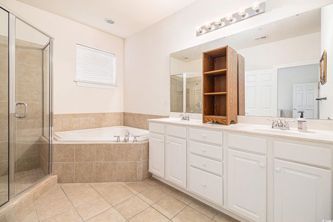 Full bath with double vanity, a bath, a stall shower, and tile patterned floors | Image 17