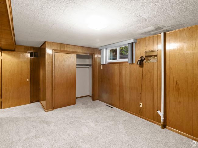 Unfurnished bedroom featuring carpet flooring, wooden walls, and a closet | Image 25