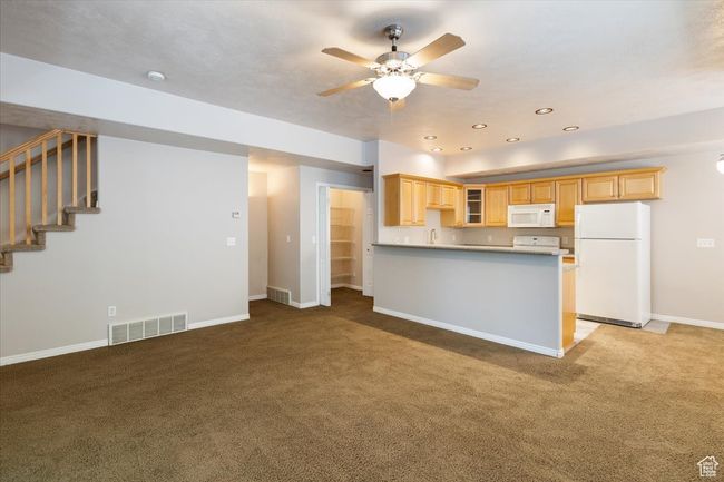 Kitchen with white appliances, carpet floors, ceiling fan, a peninsula, and recessed lighting | Image 9