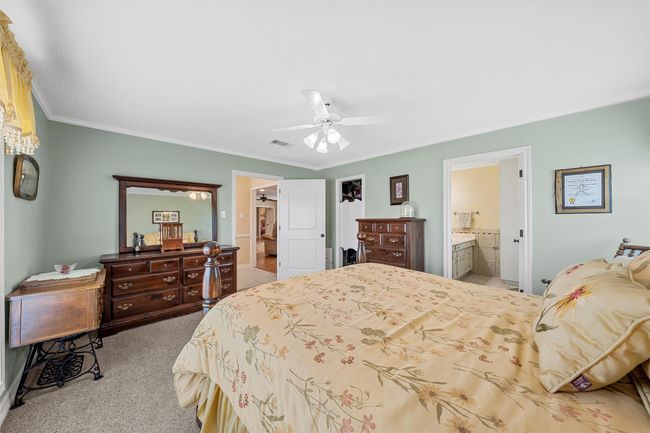 Carpeted bedroom with ornamental molding, connected bathroom, and ceiling fan | Image 16