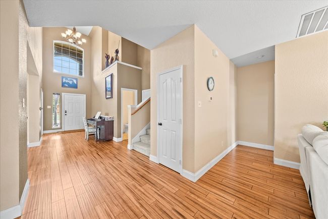 Foyer with stairway, light wood-style floors, a chandelier, baseboards, and a towering ceiling | Image 13