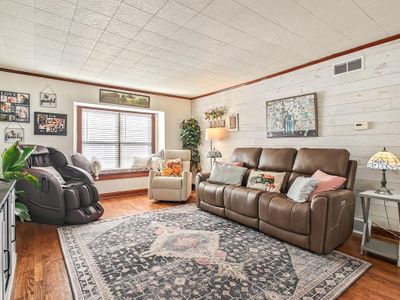 Living room featuring hardwood / wood-style floors, crown molding, and wood shiplap feature wall | Image 3