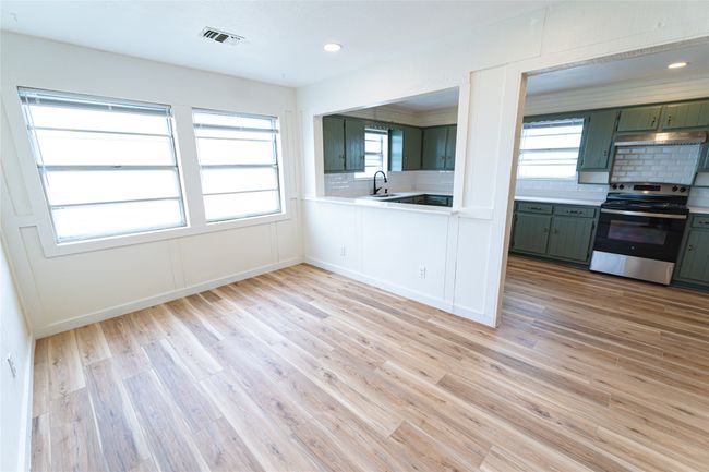 Kitchen with tasteful backsplash, light countertops, light wood-style flooring, stainless steel range with electric stovetop, and a sink | Image 13