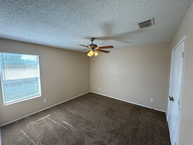 Carpeted empty room with ceiling fan and a textured ceiling | Image 19