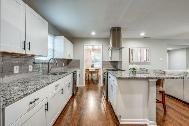 Kitchen with island range hood, appliances with stainless steel finishes, a kitchen breakfast bar, open floor plan, and dark wood-type flooring | Image 20