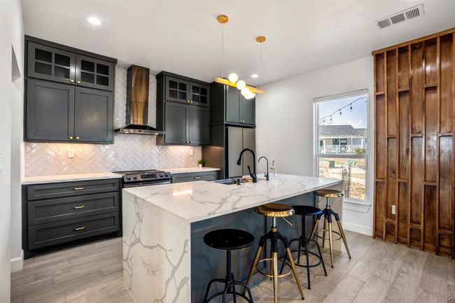 The other building's kitchen features modern finishes, a large center island with seating, and plenty of space to cook and gather. | Image 29