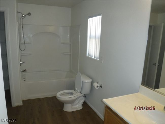 Bathroom with washtub / shower combination, vanity, toilet, baseboards, and wood finished floors | Image 8