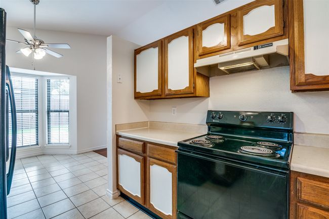 Kitchen featuring electric range, range hood, ceiling fan, light countertops, and vaulted ceiling | Image 16