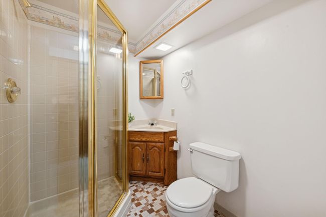 The lower level 3/4 bath features the original tile flooring and a corner shower. | Image 22