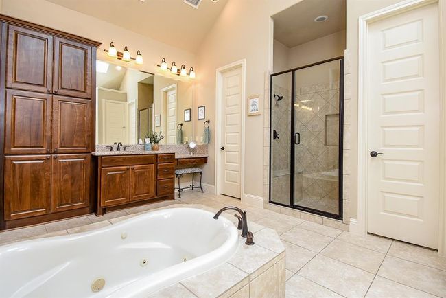 The double sinks are opposite of each other. One side features a vanity area and linen closet while the other side offers another linen closet and taller shaving sink. The separate shower has bench seating. Both walk-in closets have built-in drawers, shoes shelves and more! | Image 27