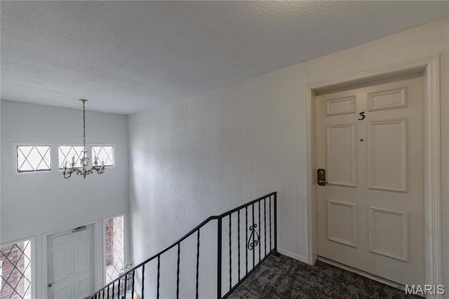 Foyer featuring a textured ceiling, a chandelier, dark colored carpet, and plenty of natural light | Image 46
