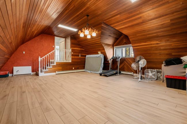 Bonus room with wooden walls, vaulted ceiling, and a baseboard radiator | Image 33