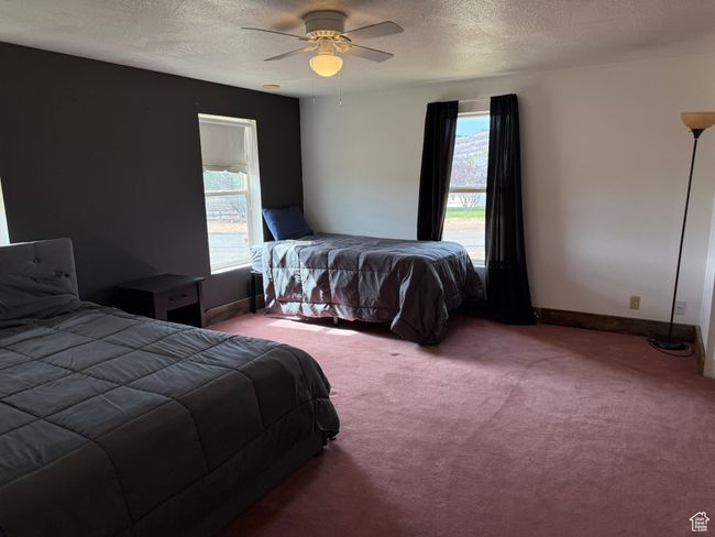 Bedroom featuring carpet floors, a textured ceiling, a ceiling fan, and baseboards | Image 7